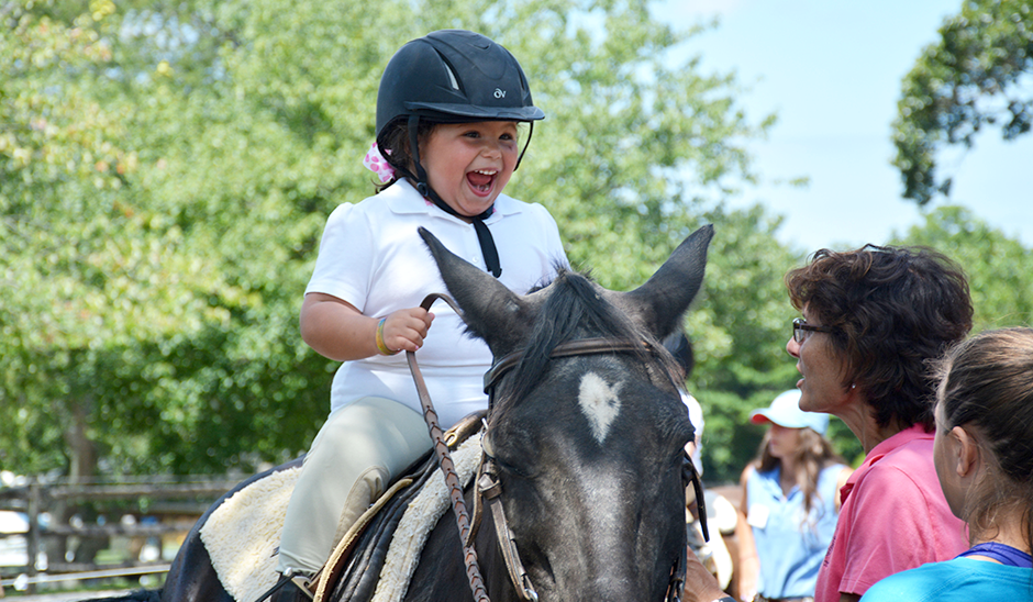 child riding horse with instructors